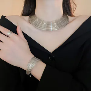 Close-up of multi-layer silver metal necklace, bracelet, and ring set on model