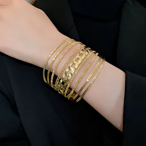 Gros plan d'un ensemble de bracelets joncs dorés minimalistes et géométriques.