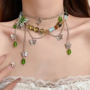 Dettaglio di una collana di perle a farfalla multistrato con cristalli verdi su collo modella