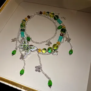 Dettaglio di una collana a farfalla multistrato con perle di vetro verdi e ciondoli argentati