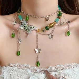 Primo piano di una collana a farfalla a più strati con perle verdi e strass.