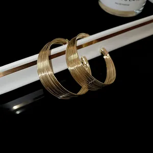 Close-up of geometric multi-layer gold hoop earrings with high-shine designer metallic finish