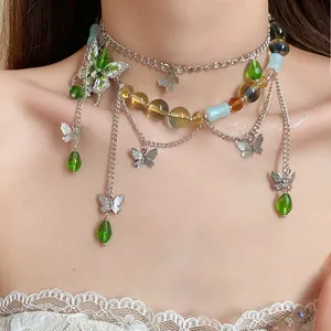 Primo piano di una collana a catena argentata con perle di vetro verdi e ciondoli a farfalla