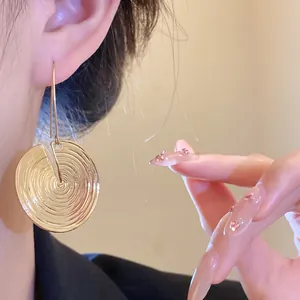 Nahaufnahme eines Models mit goldenem, rundem strukturiertem Ohrring mit Riffeldesign
