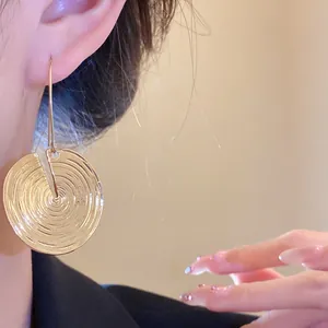 Nahaufnahme von goldenen runden Ohrhängern mit einzigartiger konzentrischer Textur