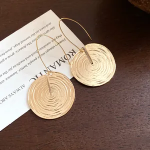 Makro-Detail von eleganten goldenen runden Ohrhängern mit konzentrischer Spiralstruktur