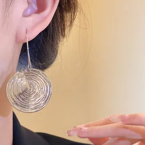 Nahaufnahme von runden silbernen Ohrhängern mit Struktur an einem eleganten Model