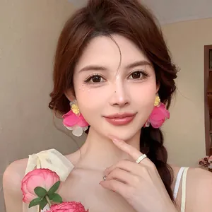 Beautiful model wearing oversized pink and yellow chiffon flower stud earrings for a fairy-like summer look