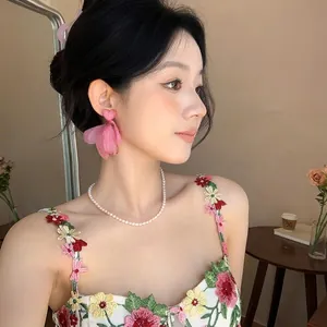 Close-up of pink chiffon flower earrings with a heart-shaped stud on an Asian model.