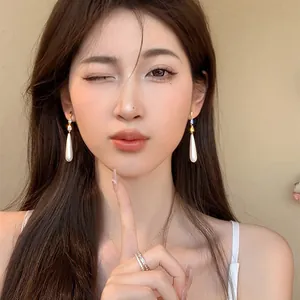 Gros plan du mannequin portant d'élégantes boucles d'oreilles perles vintage et zircon