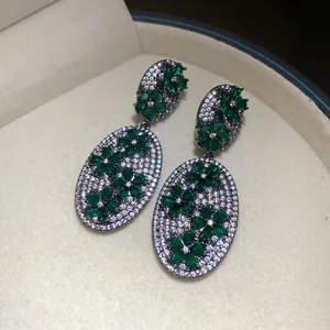 Macro detail of emerald green flower earrings with shimmering white zircon stones