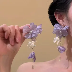 Elegant purple fabric flower dangle earrings with pearl and crystal tassel details.