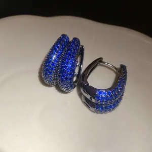Detailed macro view of vintage style double-row blue zircon paved silver hoop earrings