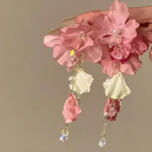 Close-up of elegant pink fabric flower earrings with pearl and crystal tassels