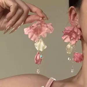 Detailed close-up of pink fabric flower tassel earrings with crystals on an Asian model.