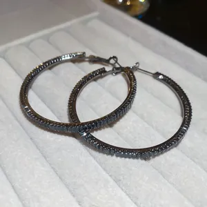 Macro detail of elegant gunmetal hoop earrings encrusted with shimmering black zircon stones