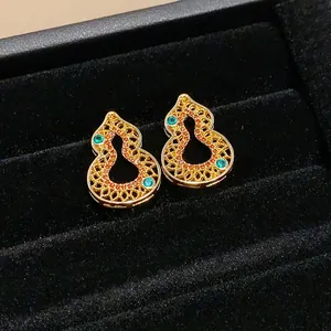 Close-up of vintage-style gourd earrings with colorful zircon stones on black velvet.