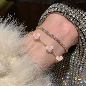 Primo piano del set bracciale tennis con zirconi e catena con fiori in madreperla rosa