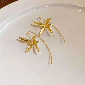 Vista dettagliata di eleganti orecchini a amo a forma di iris dorati con finitura satinata