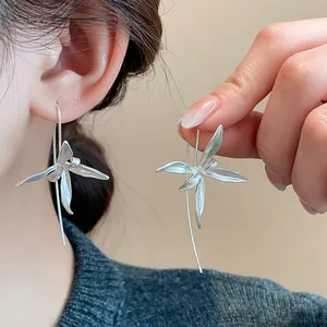Dettaglio di eleganti orecchini a gancio con iris in argento indossati e in mano