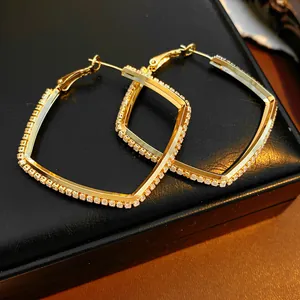Close-up detail of elegant gold geometric hoop earrings featuring micro-paved cubic zirconia