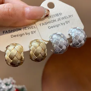 Primer plano de pendientes en forma de C con textura tejida en plata y oro