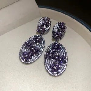Close-up of vintage-style zircon earrings with purple and white floral patterns.
