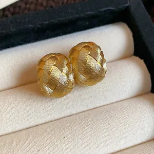 Primer plano macro que muestra la intrincada textura tejida dorada de estos pendientes