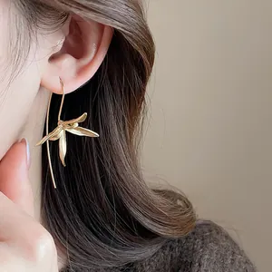 Primo piano di orecchini vintage a gancio a forma di iris in oro indossati sull'orecchio.
