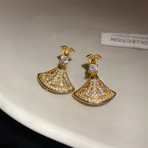 Close-up view of elegant vintage gold fan-shaped earrings with micro-pave zircon detail.