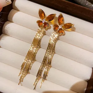 Detailed macro view of vintage style gold butterfly tassel earrings featuring amber zircons