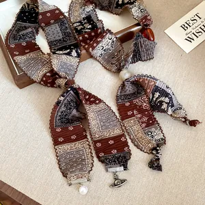 Close-up of ethnic print fabric necklace with pearl and Saturn orb pendant detail