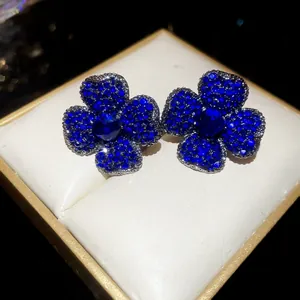 Detailed macro shot of vintage-style blue zircon flower stud earrings in a luxury box