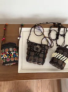Detail view of three bohemian coconut shell necklaces and mini pouches on a display tray.