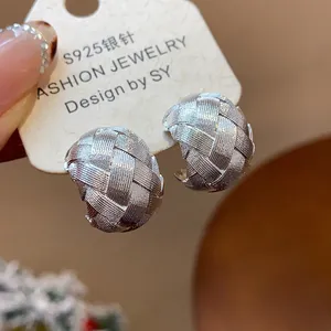 Primer plano de pendientes en C plateados con fina textura trenzada y acabado mate