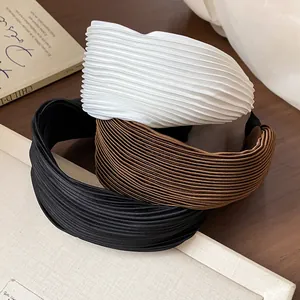 Detailed macro view of high-crown wide headbands in black, brown, and white pleated fabric