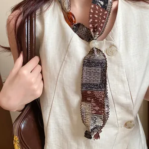 Detail shot of vintage paisley fabric necklace featuring pearl and Saturn style pendant charms.