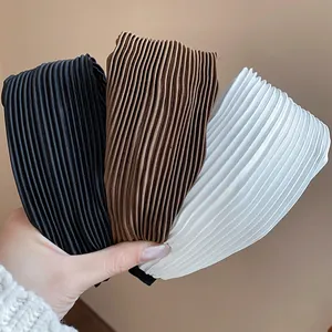 Close-up of pleated fabric headbands in black, brown, and white textures