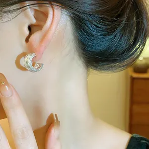 Detalle de primer plano de un pendiente de plata en forma de C texturizado en la oreja