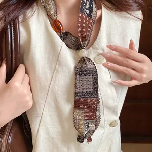 Close-up of vintage ethnic fabric necklace with amber bead and Saturn pearl pendant