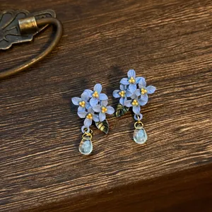 Elegante oorbellen met blauwe bloemen, groene bladeren en heldere druppelhangers.