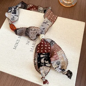 Detailed view of vintage paisley fabric choker necklace featuring pearl and amber bead
