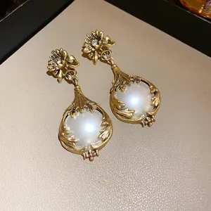 Detailansicht von goldenen Vintage-Blumenohrhängern mit großem Perlen-Cabochon-Akzent