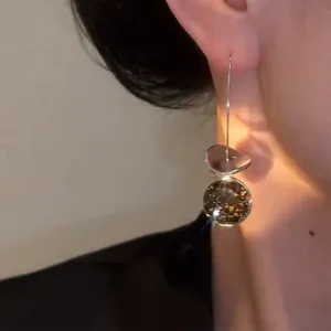 Detail view of a geometric sequin drop earring featuring a large sparkling rhinestone.