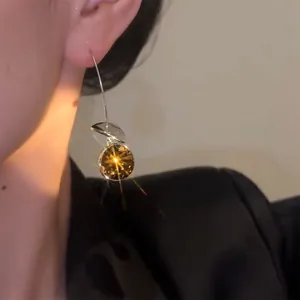 Close-up view of a sparkling geometric round crystal ear hook earring worn by a model
