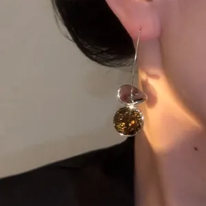 Close-up detail view of vintage geometric hook earrings with brown sequins on an ear