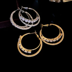 Detailed macro shot of 18k gold plated double-layered zircon hoop earrings on dark background