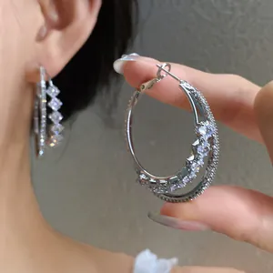 Detailed view of silver hoop earrings with shimmering cubic zirconia layers.