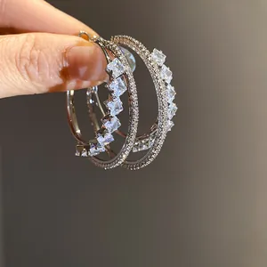 Macro detail of silver double-layered hoop earrings featuring sparkling square zircons