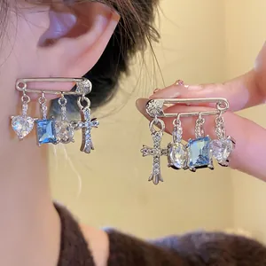 Detail of silver safety pin earrings featuring blue and clear cubic zirconia charms